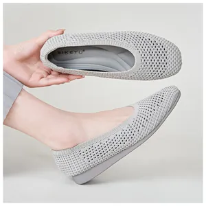 Dettaglio del tessuto in maglia traspirante su scarpe grigio chiaro con zeppa bassa