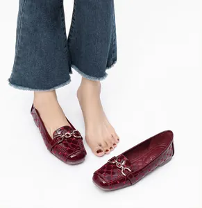Detail van bordeauxrode laklederen loafers met gouden ketting en gewatteerde stiksels