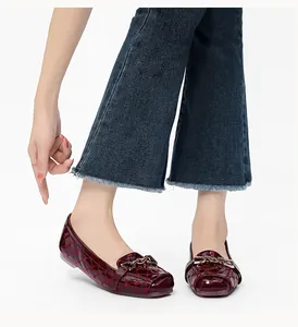 Detail van bordeauxrode laklederen platte schoen met hartstiksels en ketting