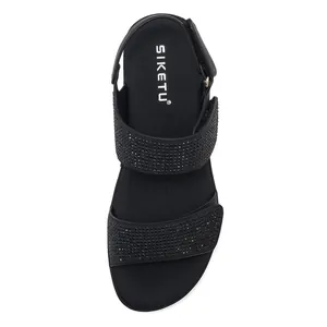 Close-up of black platform sandals featuring dual rhinestone straps and SIKETU branding