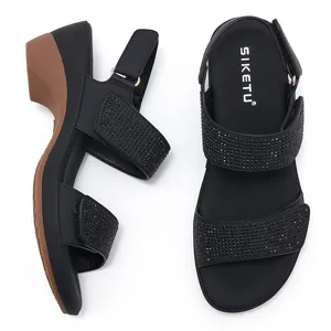 Close-up of black wedge sandals featuring rhinestone embellishments and Velcro straps