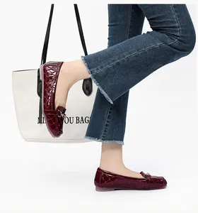 Detail van bordeauxrode laklederen loafers met gewatteerde textuur en gouden gesp