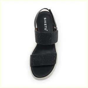 Detailed top view of black wedge sandals with rhinestone straps and brand logo detail