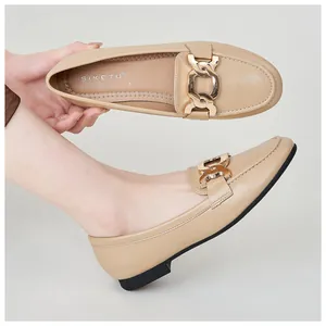 Close-up of beige leather loafers featuring an elegant gold chain buckle and black sole