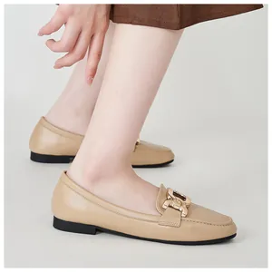 Close-up of apricot leather loafers with elegant gold metal chain buckle detail