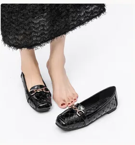 Detail van zwarte lakschoenen met ruitpatroon en gouden schakelgesp op de voet
