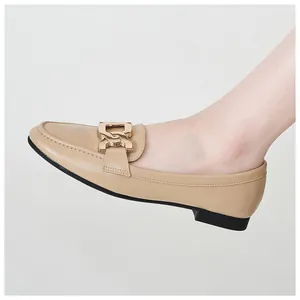 On-foot side view of beige loafers with gold chain detail and black rubber sole