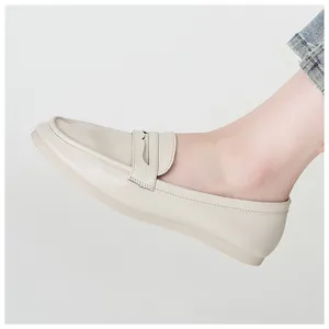 Detail of off-white leather penny loafers with a round toe and flat anti-slip sole on foot