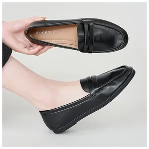 Close-up of black leather penny loafers showing premium stitching and brand logo on the insole
