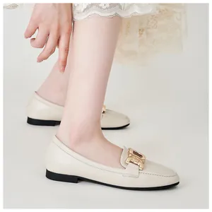Detail of off-white loafers featuring a golden chain buckle on matte leather finish