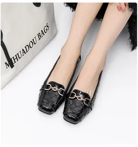 Detail van zwarte lakleren loafers met gewatteerde textuur en gouden horsebit-gesp
