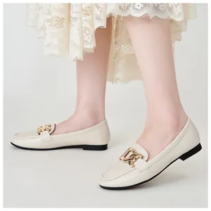 Detailed macro view of beige loafers featuring a polished gold metal buckle accent