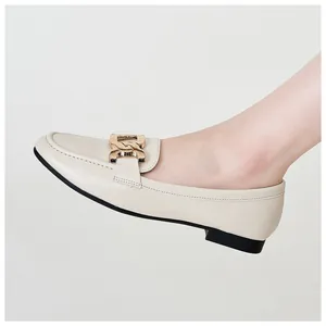Close-up of a cream-colored leather loafer with an elegant gold metal buckle detail