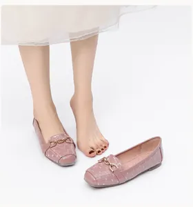 Detail van lichtroze lakschoenen met ruitpatroon en goudkleurige metalen kettingspalk