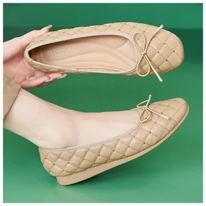 Detail von beigefarbenen gesteppten Ballerinas mit Metallnieten und einer Schleife