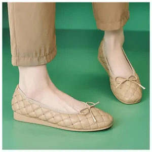 Beige gesteppte Ballerinas mit Nieten und klassischer Schleife auf grünem Grund