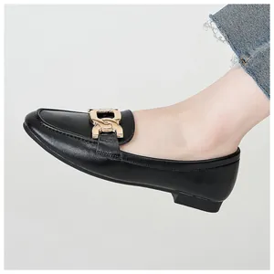Close-up of black leather loafer featuring a stylish gold metal chain buckle detail