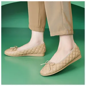 Detailansicht beige Ballerinas mit Steppmuster, Nieten und Schleife auf grünem Grund