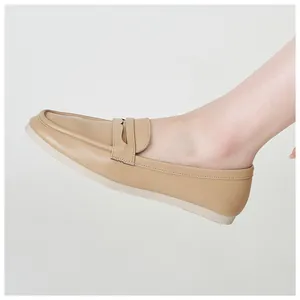 Side view of comfortable khaki leather loafers worn on feet with a minimal white background