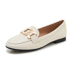 Close-up of beige leather loafers featuring a chunky gold metal chain buckle detail