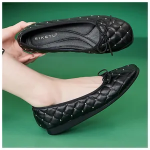 Detail eines schwarzen gesteppten Ballerinas mit Goldnieten und zarter Schleife