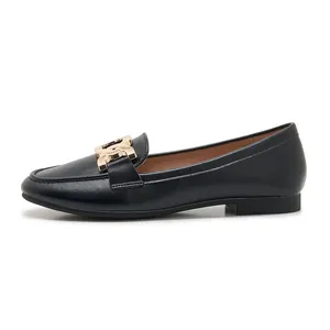 Detail of black matte leather loafers featuring a distinctive gold metal buckle ornament