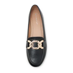 Close-up of black leather loafer featuring a stylish oversized gold chain buckle detail