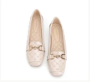 Detail van beige lakschoenen met gewatteerd patroon en gouden bit-gesp versiering