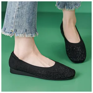 Detail view of black knit flat shoes with rhinestones and elastic ankle on a model