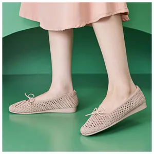 Detailed view of breathable knitted mesh fabric and bow ornament on pink flat shoes