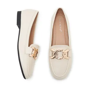 Detail view showing beige leather loafers with golden chain and comfortable rubber sole