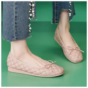 Details von hellrosa gesteppten Ballerinas mit Goldnieten und Schleife auf grünem Grund