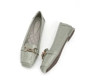 Detail van grijze gewatteerde platte schoenen met gouden ketting en glanzende afwerking