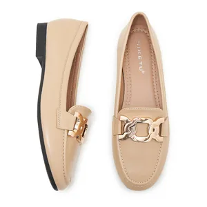 Detail view of beige loafers featuring a stylish oversized gold chain buckle decoration