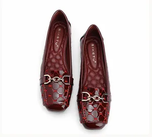 Detail van wijnrode laklederen loafers met gewatteerde textuur en gouden metalen gesp