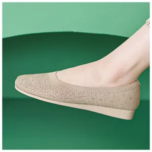 Side view of beige knitted flat shoes with rhinestone details on a green background