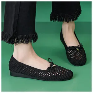 Detail of breathable black mesh flat shoes with a delicate bow and gold hardware accent