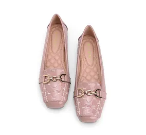 Close-up van gewatteerde roze lakloafers met gouden gesp en een masserende binnenzool