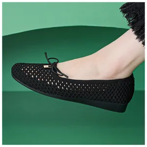 Close-up of black breathable knit flat shoes featuring bow detail and gold hardware