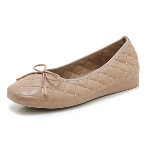 Detail von hellbraunen gesteppten Ballerinas mit Goldnieten und Schleifenschmuck