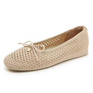 Close-up of beige woven flat shoes featuring a bow tie and gold metal pendant