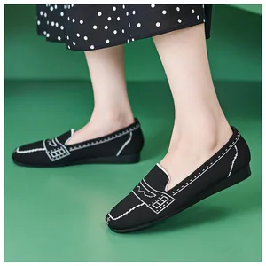 Nahaufnahme von leichtem schwarzem Strick-Loafer mit weißer Stickerei auf Grün