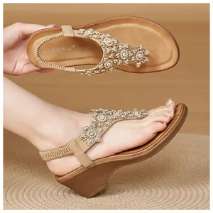 Detail of floral rhinestone and pearl patterns on beige wedge sandals with T-strap
