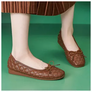 Detail brauner gesteppter Leder-Ballerinas mit Nieten und Schleife am Fuß