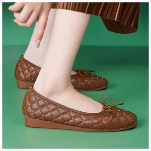 Detailansicht brauner Stepp-Ballerinas mit Metallnieten und Schleife auf grünem Grund