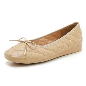 Nahaufnahme beigefarbener gesteppter Ballerinas mit Goldnieten und eleganter Schleife