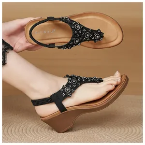 Detailed view of black rhinestone flower sandals with wood-textured wedge soles
