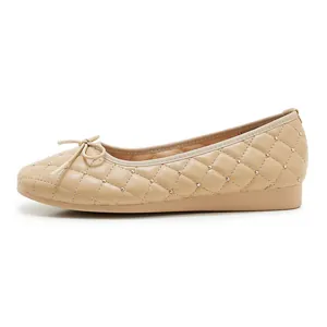 Details der beigen Ballerinas mit Steppnähten und goldenen Perlenverzierungen