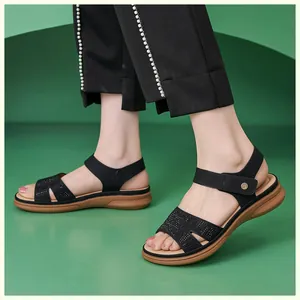 Detail of black wedge sandals featuring rhinestone straps and golden metal buckle closure