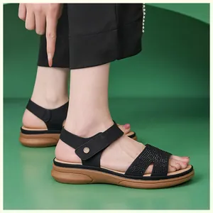 Close-up of black wedge sandals featuring sparkling rhinestones and golden metal logo detail